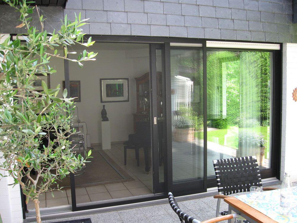 Große Schiebe-Terrassentür mit Blick in den Garten, halb geöffnet, mit Schiebe-Fliegengitter.